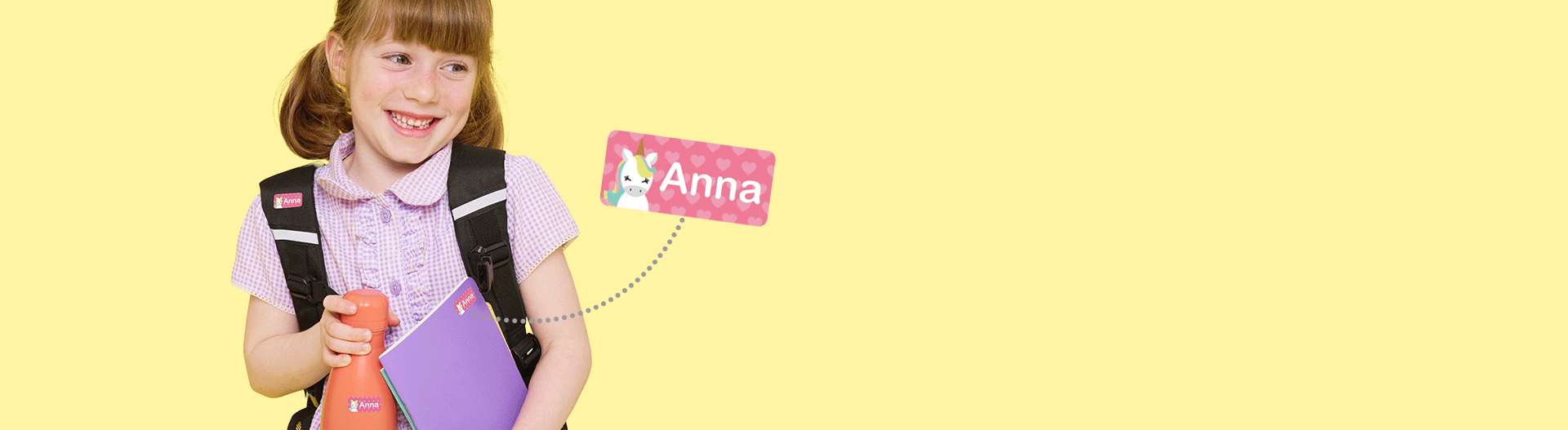Child holding a notebook and water bottle with personalised name labels