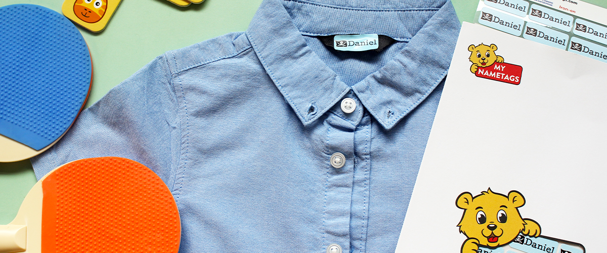 My Nametags iron on label atttached to a blue shirt, on a light green background