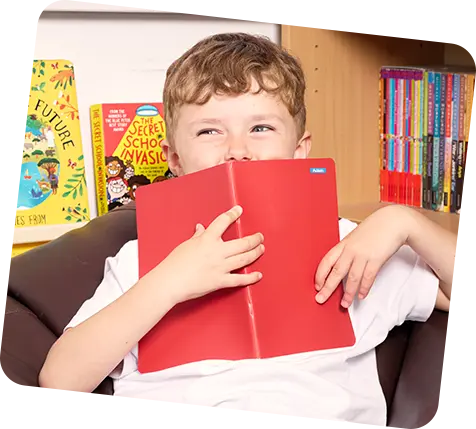 Little boy holding book in front his face. Book has a ministicker label on it.