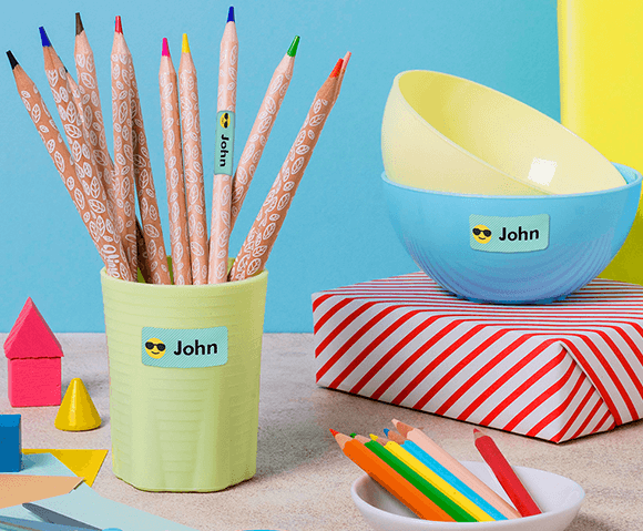 My Nametags colour name stickers on a bowl and pencils in a cup, on a blue and yellow background